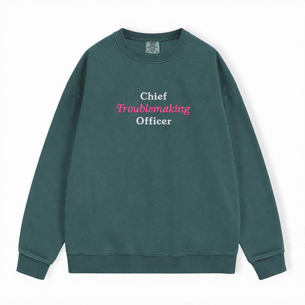 A dark green crewneck sweatshirt with the text 'Chief Troublemaking Officer' printed on the chest in white and pink, displayed flat against a white background.