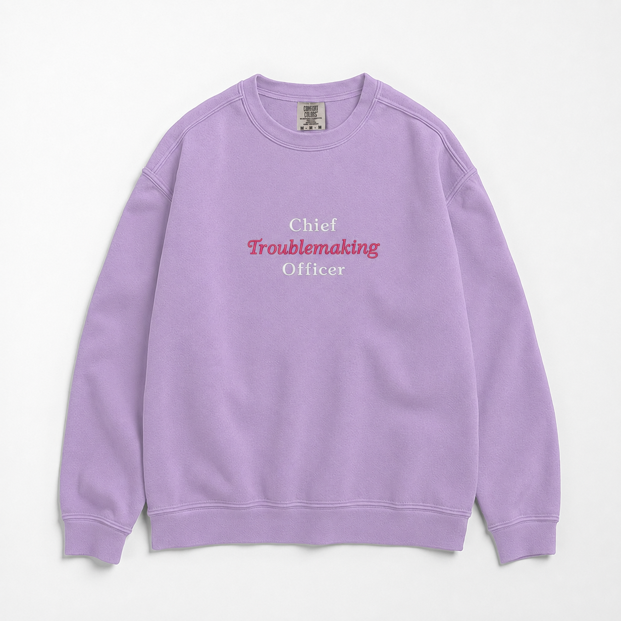 A light purple crewneck sweatshirt with the text 'Chief Troublemaking Officer' printed on the chest, featuring white and pink lettering, laid flat against a light off-white background.