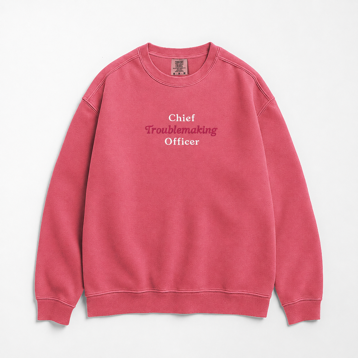 A pink crewneck sweatshirt with the text 'Chief Troublemaking Officer' printed on the chest in white and pink lettering, displayed flat against a light gray background.