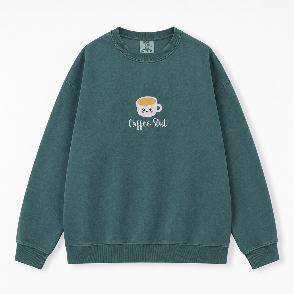 A dark green crewneck sweatshirt featuring a cute cartoon coffee cup embroidered with the text 'Coffee Slut' below in white script, displayed on a clean white background.