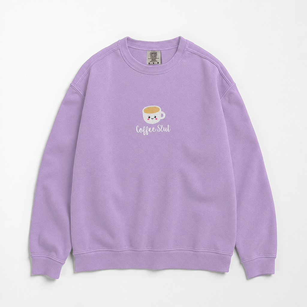 A light purple crewneck sweatshirt featuring a small embroidered coffee cup with the text 'Coffee Slut' on the chest, displayed against a clean white background.