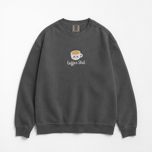 A dark gray crewneck sweatshirt featuring a cute cartoon coffee cup embroidered with a smiling face and the text 'Coffee Slut' written below it, displayed on a clean white background.