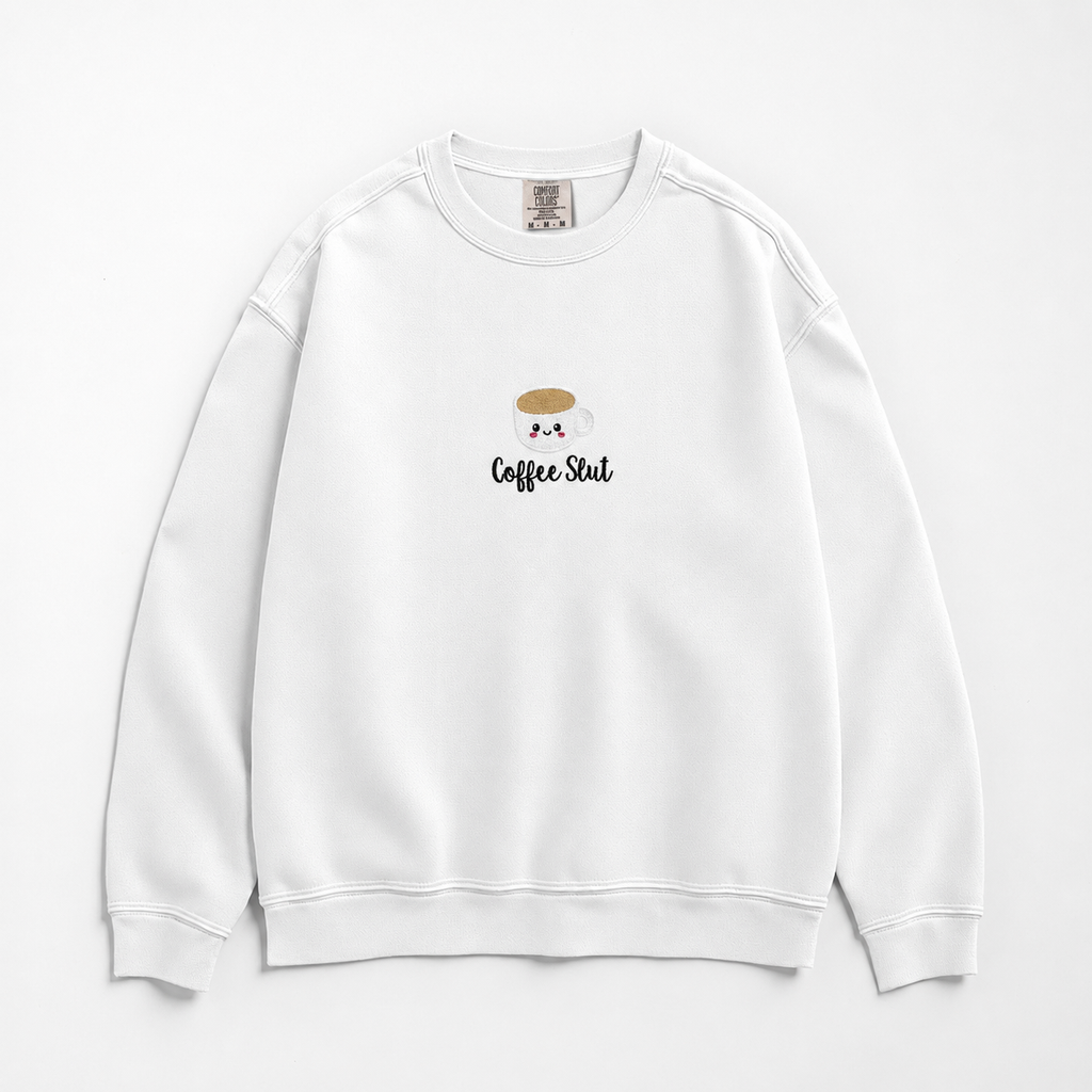 A white crewneck sweatshirt featuring a small embroidered coffee cup with the text 'Coffee Slut' on the chest, displayed against a clean white background.