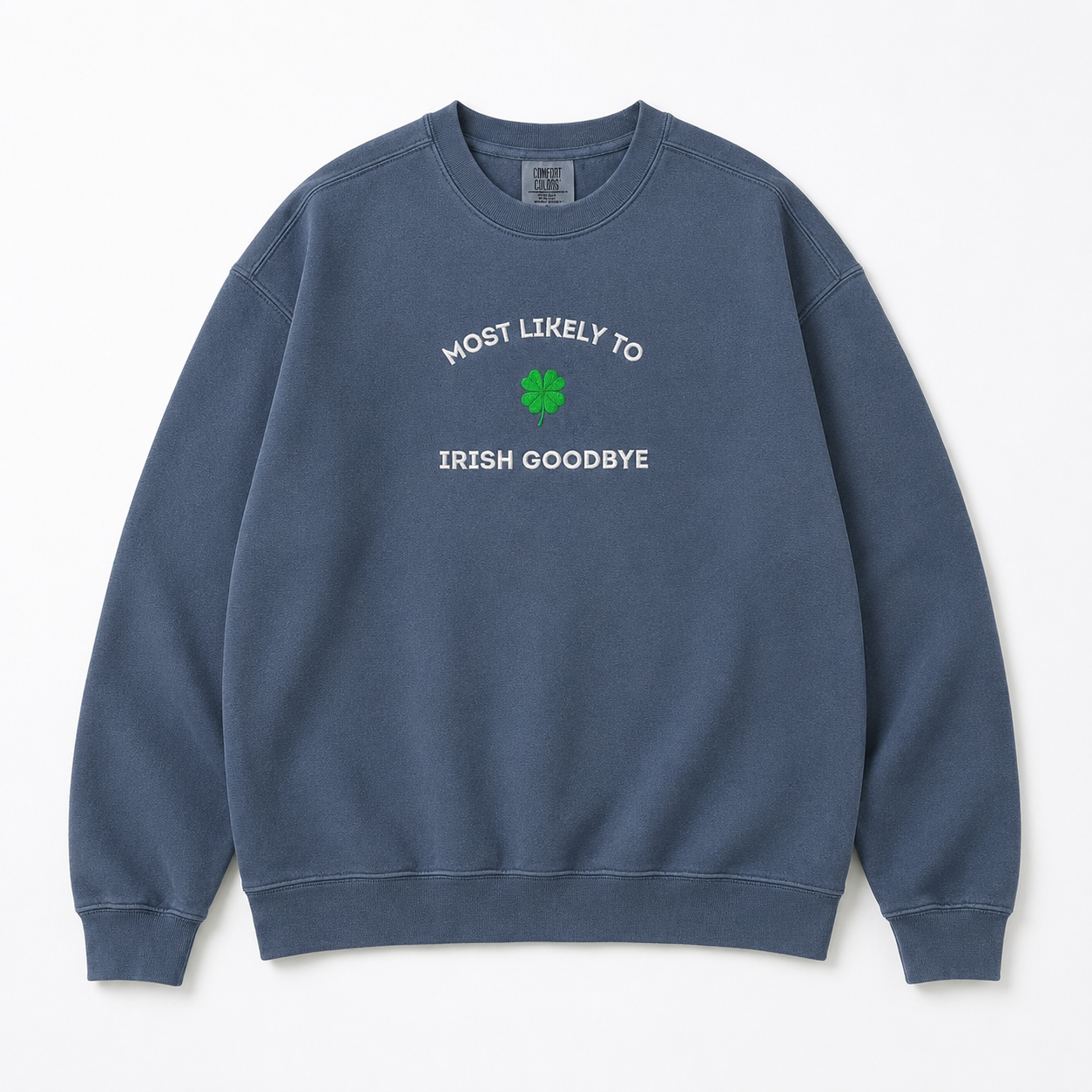 A faded blue crewneck sweatshirt embroidered with white text reading 'MOST LIKELY TO IRISH GOODBYE' and a green four-leaf clover graphic on the chest, displayed flat against a light off-white background.