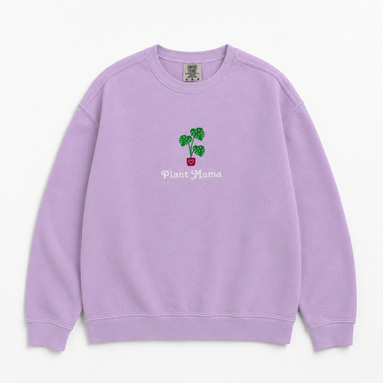 A lavender crewneck sweatshirt featuring an embroidered monstera plant in a pink pot and the text 'Plant Mama' on the chest, displayed against a clean off-white background.