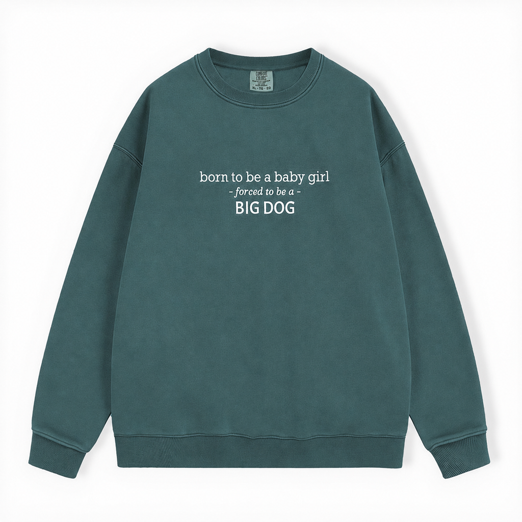 A dark green crewneck sweatshirt with white text on the chest reading 'born to be a baby girl -forced to be a - BIG DOG', displayed flat against a plain white background.
