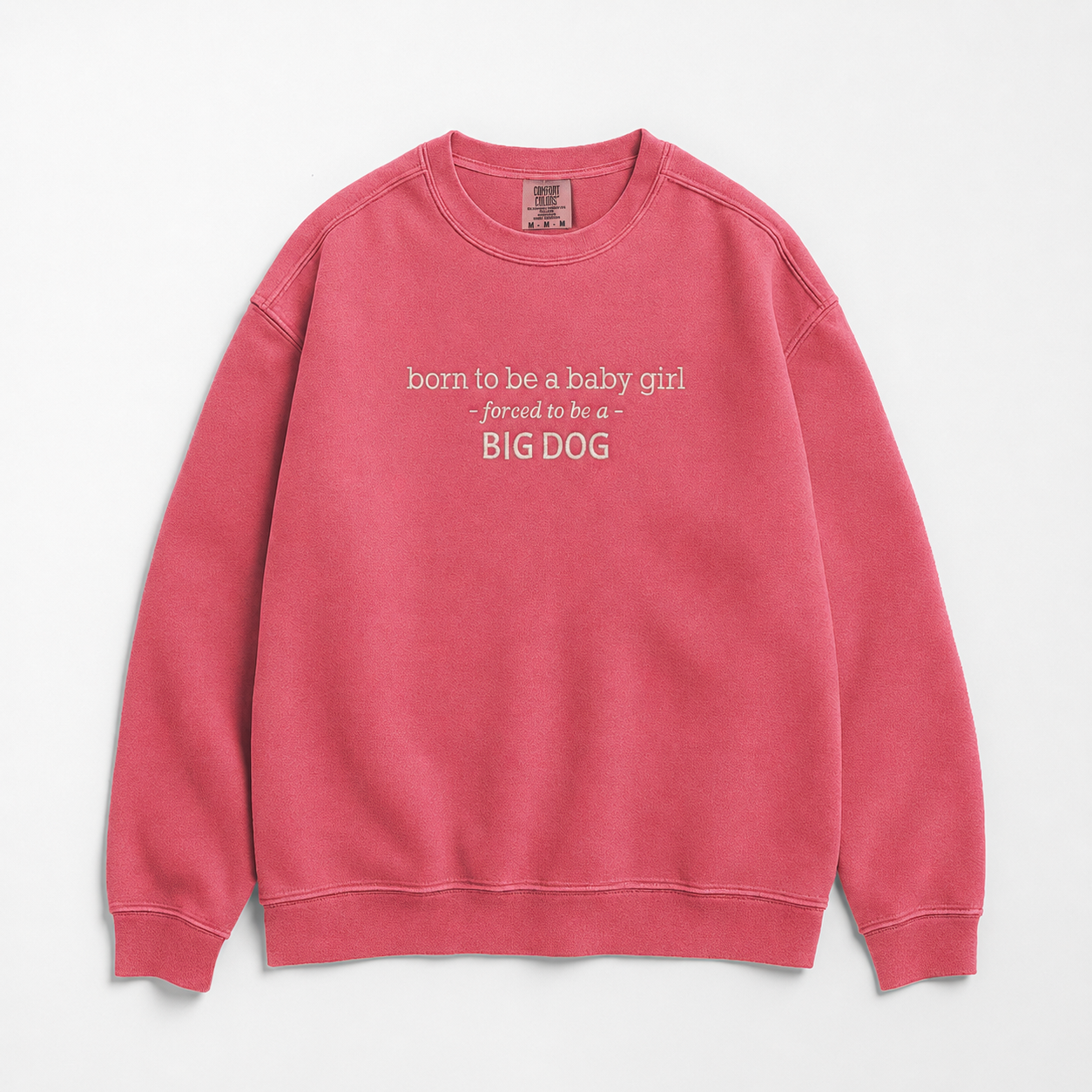 A pink crewneck sweatshirt with white text on the chest reading 'born to be a baby girl forced to be a - BIG DOG', displayed flat against a light gray background.