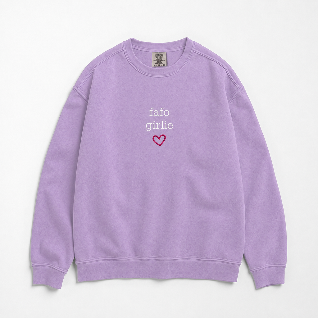 A lavender purple crewneck sweatshirt featuring the text 'fafo girly' in white and a small pink heart outline on the chest, displayed flat against a light off-white background.