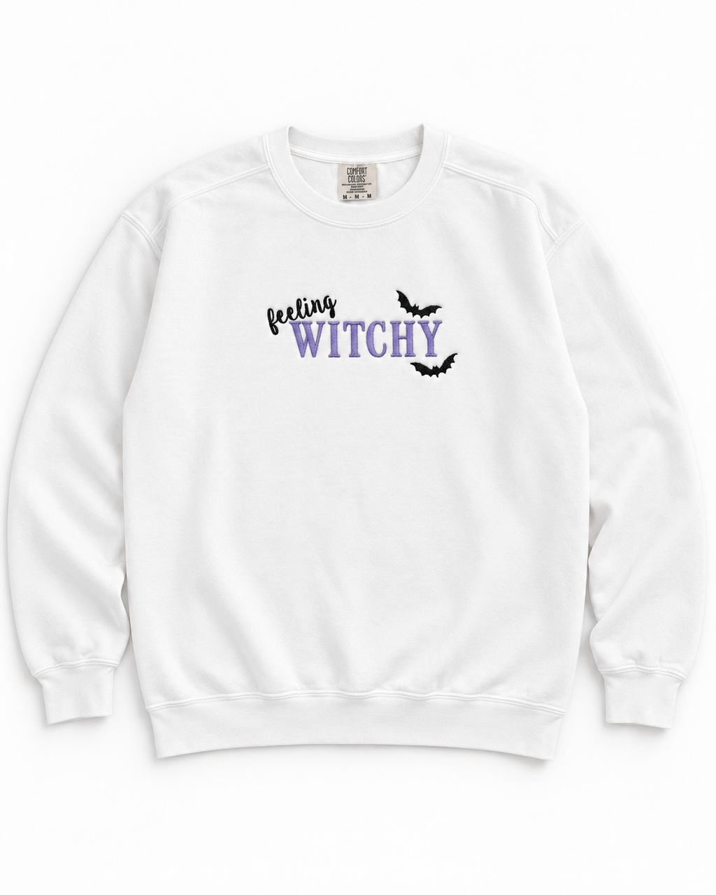 A white crewneck sweatshirt featuring a graphic on the chest that reads 'feeling WITCHY' in black and purple lettering, accented with two small black bat silhouettes, shown against a plain white background.