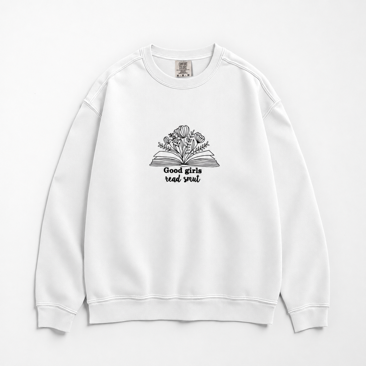 A white crewneck sweatshirt featuring a black line art graphic of an open book with flowers growing out of it and the text 'Good girls read smut' printed below, displayed on a clean white background.
