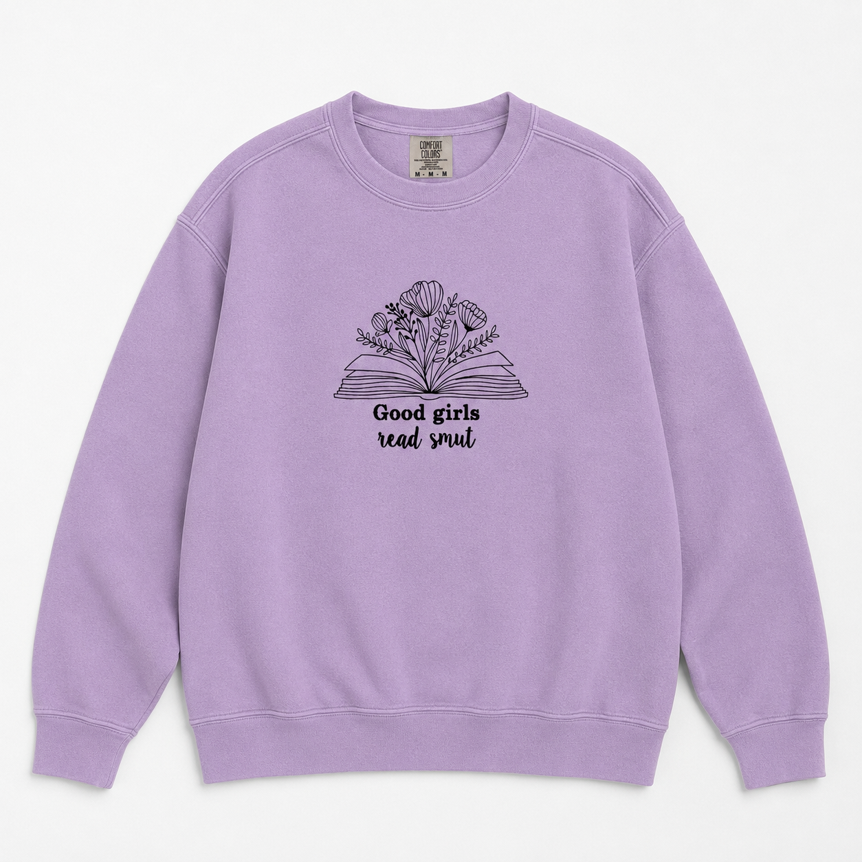 A lavender crewneck sweatshirt featuring a black line art graphic of an open book with flowers growing from it and the text 'Good girls read smut' printed on the chest, displayed against a clean off-white background.