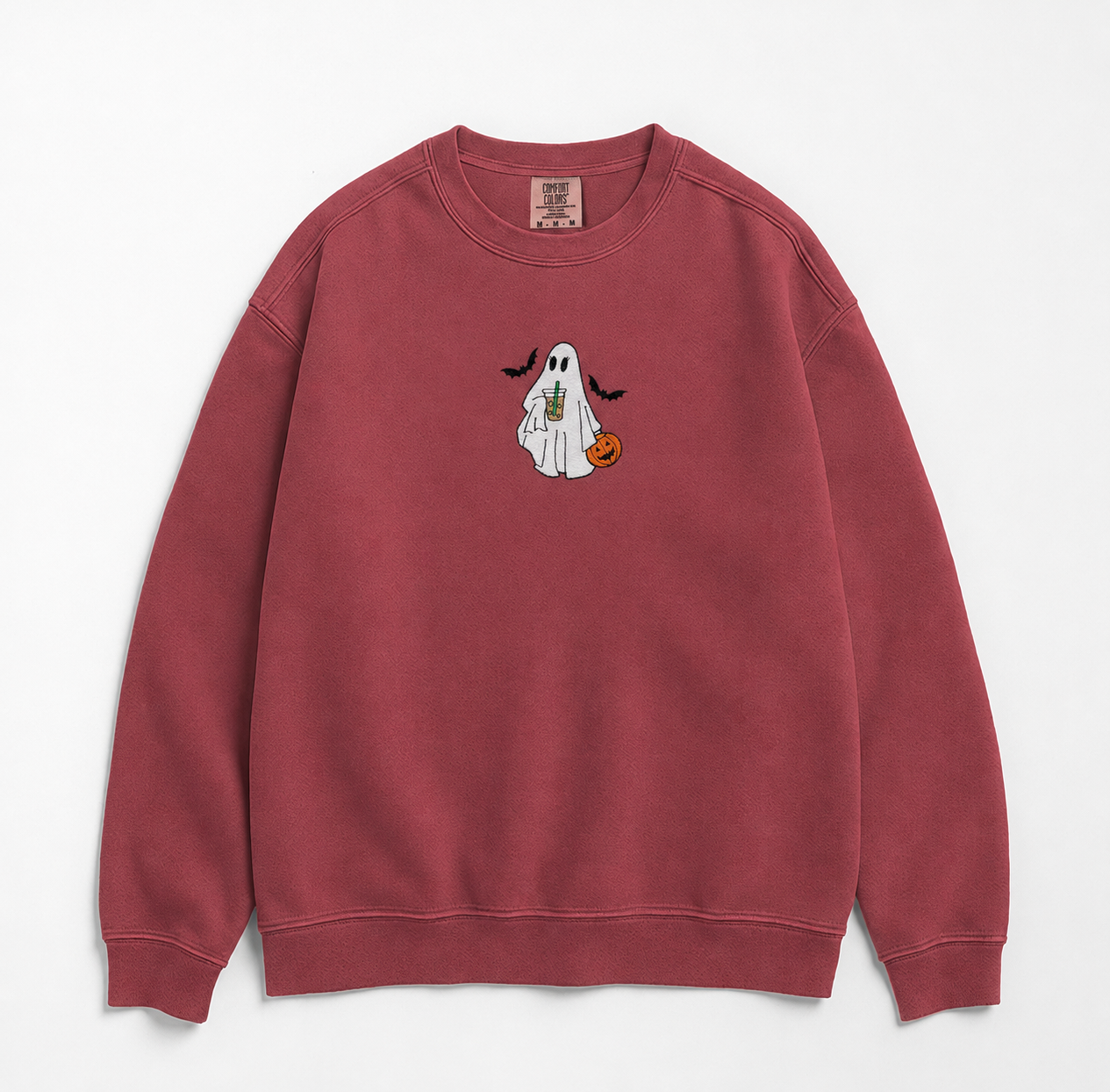 A dusty rose crewneck sweatshirt featuring a small embroidered Halloween graphic of a white ghost holding an iced coffee and a small orange pumpkin, displayed on a clean white background.
