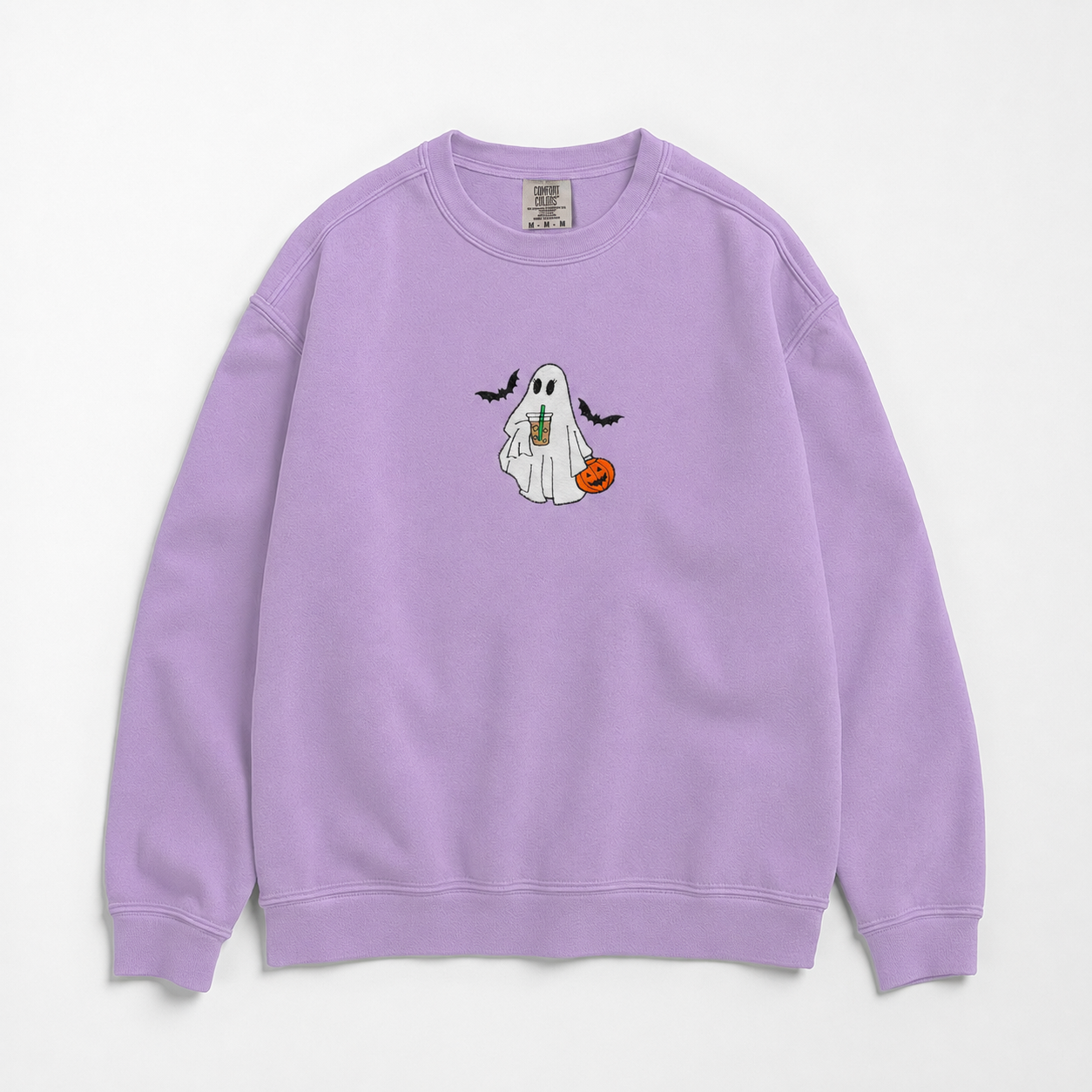 A lavender purple crewneck sweatshirt featuring a cartoon graphic of a white ghost holding a pumpkin  and iced coffee. The ghost is surrounded by bats on the chest, displayed flat against a light off-white background.