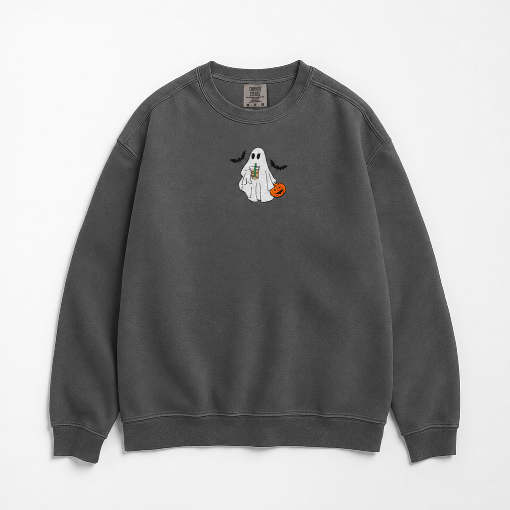 A dark gray crewneck sweatshirt featuring a small Halloween graphic of a white ghost holding a pumpkin and iced coffee. The ghost is flocked by two bats, and the design is on the center chest, displayed against a clean white background.