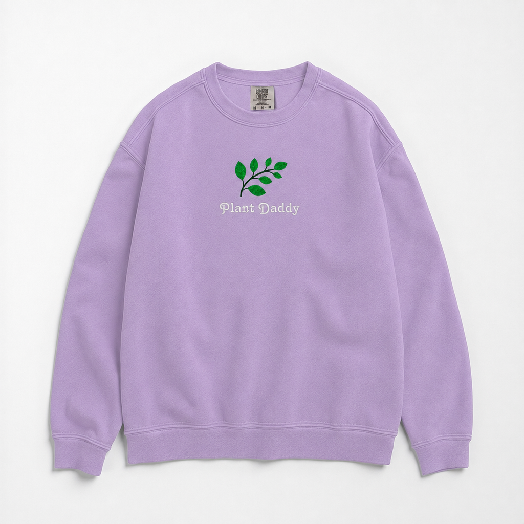A light purple crewneck sweatshirt featuring an embroidered green leaf graphic and the text 'Plant Daddy' on the chest, displayed flat against a light gray background.