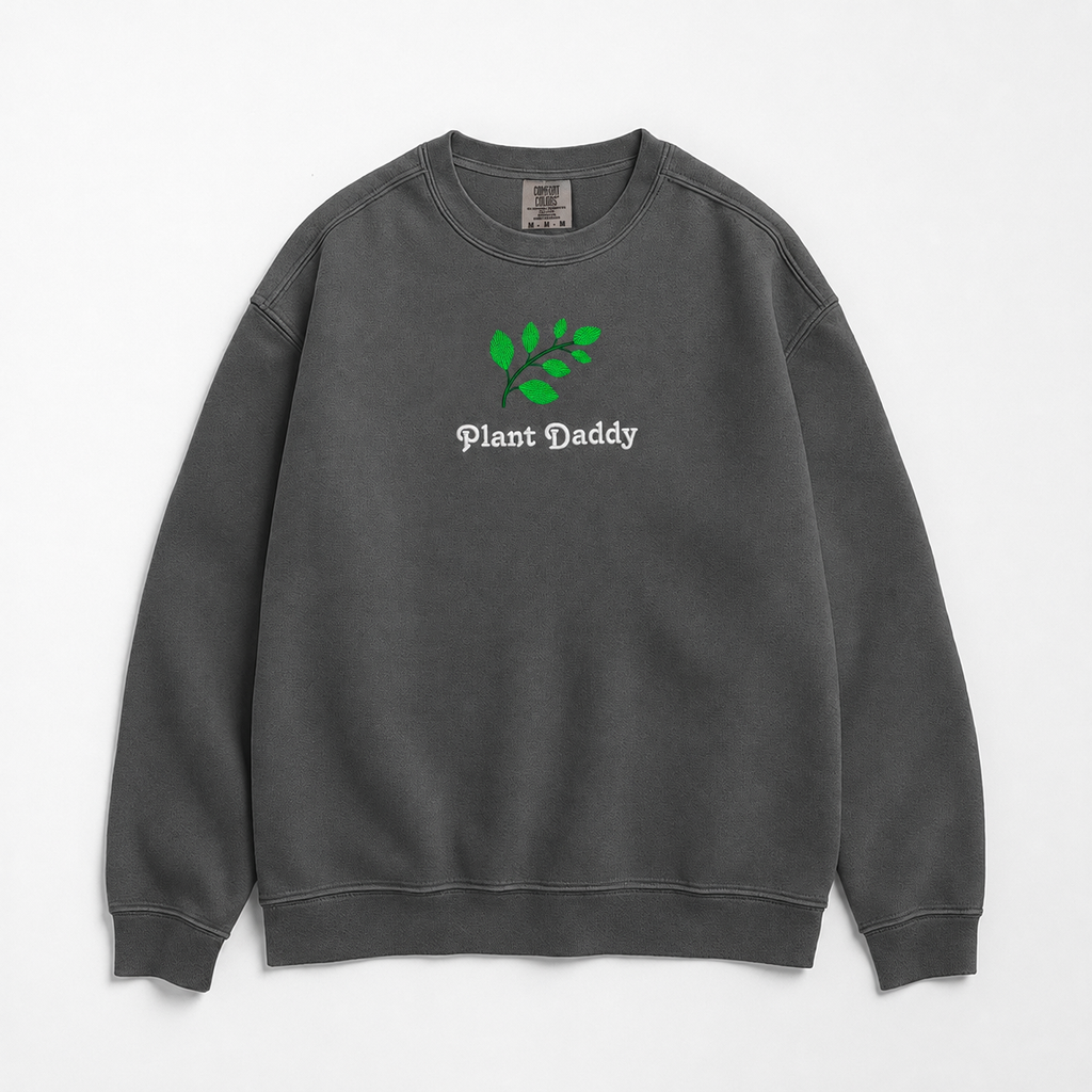 A dark gray crewneck sweatshirt featuring an embroidered green leaf graphic and the text 'Plant Daddy' on the chest, displayed flat against a light gray background.